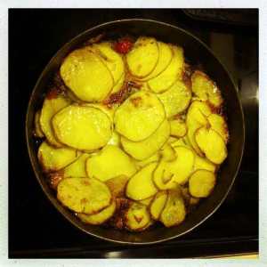 Thinly sliced potatoes layered with spinach, tomatoes and olives